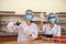 Chemists working in laboratory. Young women in protective uniforms with test tubes making experiments