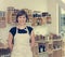 Cherfull young female shop owner posing in front of shelves full of healthy products.