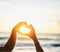 Cherish every sunset. a couple forming a heart shape with their hands at the beach.