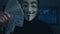 Cherkassy, Ukraine, January 04 2019: anonymous in Guy Fawkes mask recounts bills of dollars earned for cybercrime