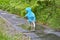 Cherkasy, Ukraine, June 13, 2019 - Blue Cookie monster funny riding white bicycle on wet path among plants, back view