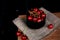 Cherries in glass bowl on the sacking on black background. Rustic organic home-grown berries. Cozy countryside dinner