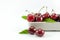 Cherries are housed in white ceramic vessels on a white floor.