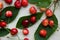 Cherries with leaves and stalks, scattered on a light background