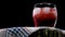 Cherry alcoholic drink with ice on a black background, cherry juice in a transparent glass, a person puts a drink of a red hue