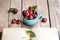 Cherry in the beautiful turquoise cup and old book on a wooden table. Fruit, education