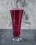 Cherry beer in tall glass goblet on gray background