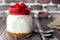 Cherry cheesecake in mason jar on wood with brick background