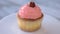 Cherry cupcake on white plate.