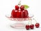 Cherry jelly on a glass stand for dessert with whole cherries above on white background