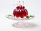 Cherry jelly on a glass stand for dessert with whole cherries above on white background