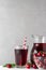 Cherry juice in a glass with a straw and jug with fresh berries on white background. Refreshment summer drink
