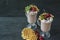 Cherry milkshake with ice cream and whipped cream, marshmallows, cookies, waffles, served in a glass cup. Dark wooden background.