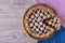 Cherry pie on light wooden boards. With linen blue and pink textile. View from above.