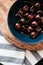 Cherry, plate, wooden form. Dark red cherries in a ceramic bowl on a wooden form and kitchen towel with a line