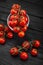 Cherry tomato branch, fresh ripe organic vegetables on dark black textured background, macro angle view