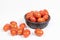 Cherry tomatoes in an African ebony wood bowl on a white background. Some cherry are fallen on the table. concept vegetable,