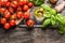 Cherry Tomatoes, basil and olive oil on wooden background, top view