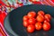 Cherry tomatoes in a black plate over colorful Mexican table top