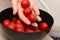 Cherry Tomatoes in a bowl in female hands. Hands cradling a black bowl filled with bright red cherry tomatoes