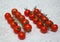 Cherry tomatoes on a branch in two rows on a table with a blanket tablecloth