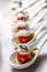 Cherry tomatoes on dessert spoons, garnished with buttercream and sliced olives