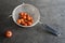 Cherry tomatoes  in metal strainer on grey concrete kitchen dresser