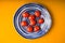 Cherry tomatoes plate on yellow wooden table. Top view