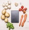 Cherry tomatoes, potatoes, carrots, parsley and mushrooms laid out around a notebook place text,frame on wooden rustic backgro