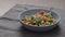 cherry tomatoes to green fettuccine with pesto in blue bowl