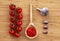 Cherry tomatoes on a wooden background. Food background. Adjika sauce in spoon and garlic on burlap. Top view, photo of food,