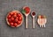 Cherry tomatoes in a wooden plate on a gray background. Adjika sauce, red and black pepper, parsley, mustard and pesto in spoons