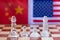 Chess board game pieces on USA and China flag background, trade war tension situation concept