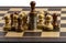 Chess board with pawns and coins, business growth or success and advantage concept