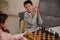 A chess game for a clever mind. Beautiful smart kids having great time, enjoying playing chess together in home interior. The