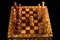 Chessboard with Queen Gambit opening on black background, carved chess