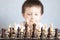 A chessboard with spaced figures, in the background a boy out of focus. Board game of chess. Tournaments and schools for young