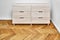 Chest of drawers with bleached solid oak stands on parquet floor. Axonometric view