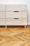 Chest of drawers with finger pull sliders on parquet floor