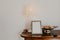 Chest of drawers with a lamp candelabra and a vase against a white wall- Image