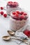 Chia milk pudding with raspberry in the glass jars decorated with fresh berries, vintage spoons on the gray kitchen background