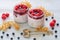 Chia milk pudding with raspberry and white currant in the glass jars on the gray kitchen table decorated with fresh berries