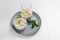 Chia pudding with banana in glass cups with a sprig of mint on a gray plate on a white background.