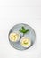 Chia pudding with banana in glass cups with a sprig of mint on a gray plate on a white background.