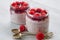 Chia pudding with fresh raspberry in the glass jars on the gray kitchen background. Summer detox superfoods breakfast
