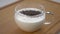 Chia seeds fall into white thick glass yogurt in a cup