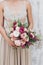 Chic beautiful wedding bouquet of peonies and roses in pastel color in hands