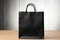 Chic black paper bag placed on a clean white wooden surface