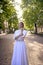 chic middle age woman in a white vintage dress in a sunlit alley