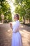 chic middle age woman in a white vintage dress in a sunlit alley